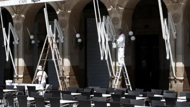 Dos empleados limpian y pintan el exterior de una cafetería en Pamplona, en una imagen de archivo. EFE/ Jesús Diges