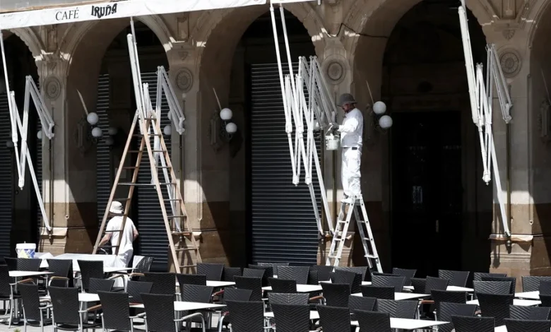 Dos empleados limpian y pintan el exterior de una cafetería en Pamplona, en una imagen de archivo. EFE/ Jesús Diges