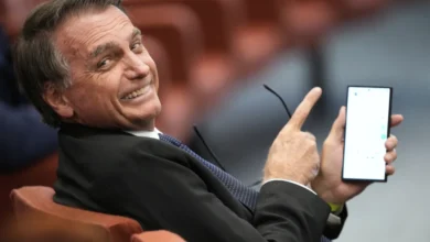 El expresidente de Brasil Jair Bolsonaro muestra la pantalla de su teléfono durante su juicio ante el Supremo Tribunal Federal mientras él y otras personas enfrentan cargos por un supuesto complot golpista para mantenerlo en el poder después de su derrota electoral de 2022, el martes 10 de junio de 2025, en Brasilia. (AP Foto/Eraldo Peres)