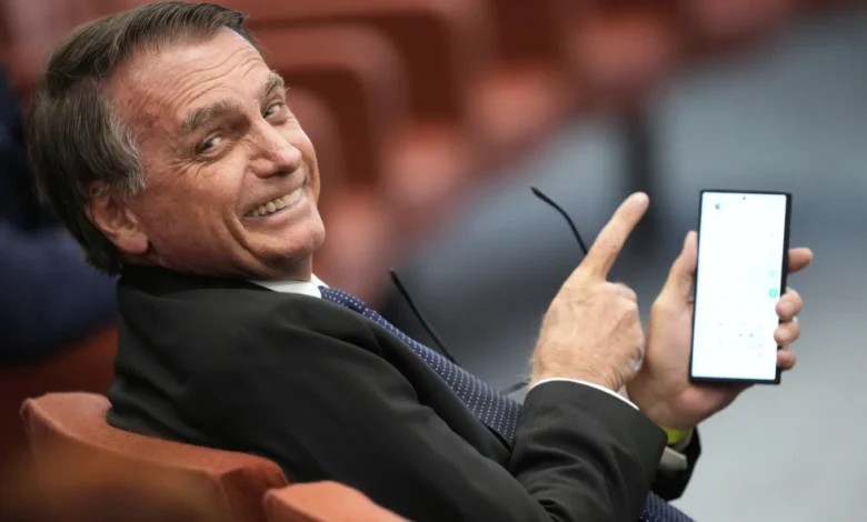 El expresidente de Brasil Jair Bolsonaro muestra la pantalla de su teléfono durante su juicio ante el Supremo Tribunal Federal mientras él y otras personas enfrentan cargos por un supuesto complot golpista para mantenerlo en el poder después de su derrota electoral de 2022, el martes 10 de junio de 2025, en Brasilia. (AP Foto/Eraldo Peres)