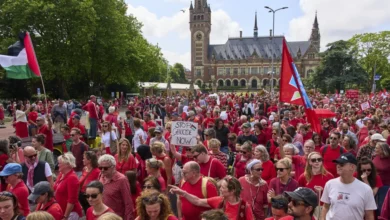 Decenas de miles de personas vestidas de rojo marchan frente al Palacio de la Paz, sede de la Corte Internacional de Justicia, al fondo, para exigir que su gobierno haga más para frenar la campaña militar de Israel en la Franja de Gaza, el domingo 15 de junio de 2025, en La Haya, Holanda. (AP Foto/Peter Dejong)